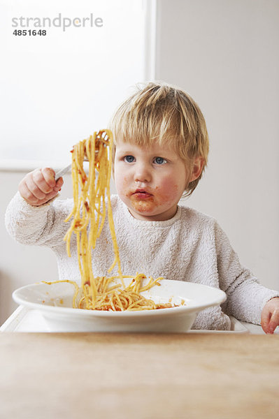 Unordentlicher kleiner Junge  der Spaghetti isst.