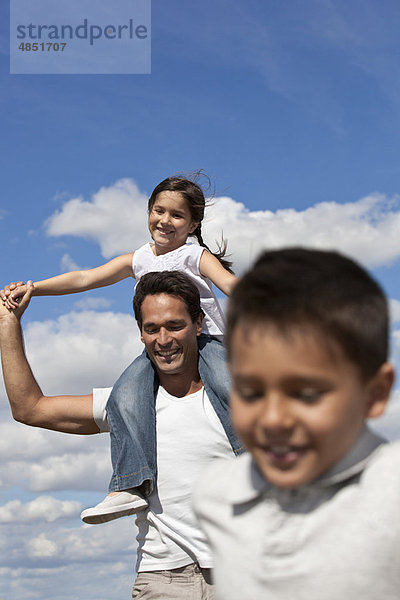 Vater mit Kindern  die auf einem Feld laufen