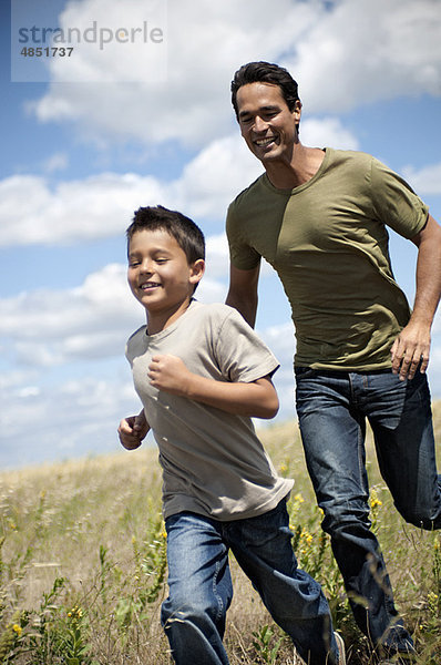 Vater und Sohn laufen durch ein Feld.