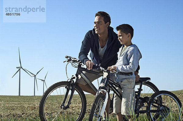Vater und Sohn mit Fahrrädern bei einem Windpark