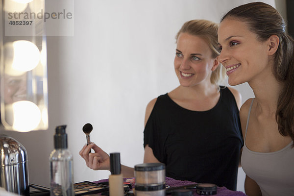 Make-up Artist & Model lächelnd im Spiegel