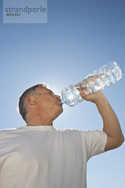 Erwachsener Mann trinkt Wasser aus der Flasche