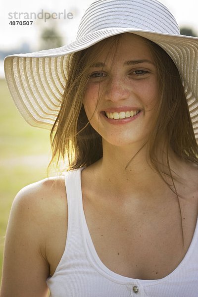 Fröhliche junge Frau mit Hut im Freien