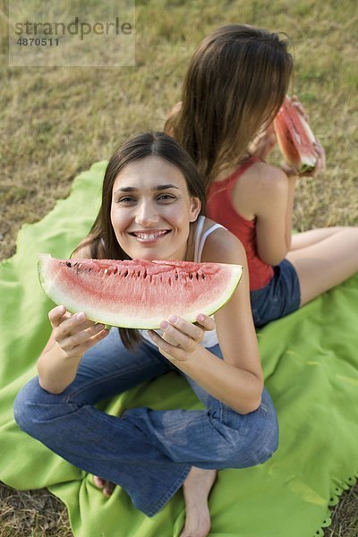 Zwei junge Frauen essen Melonen im Freien