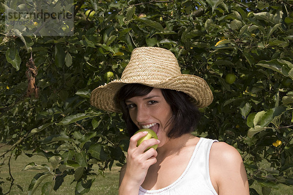 Junge Frau isst einen Apfel vom Baum  Portrait
