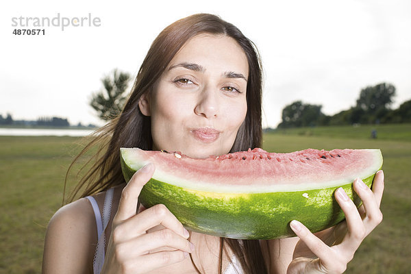 Junge Frau isst eine Melone im Freien