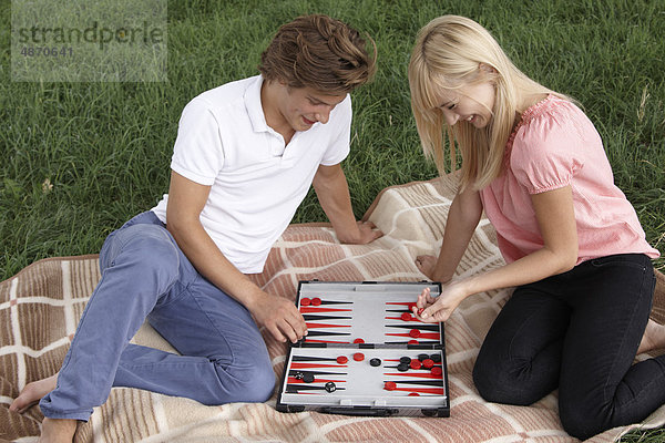 Junges Paar spielt Backgammon im Freien
