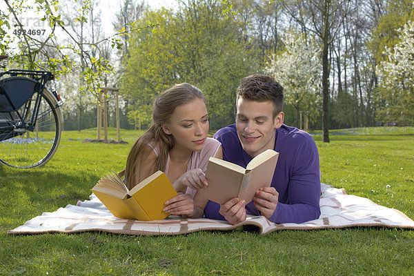Junges Paar liest auf einer Wiese