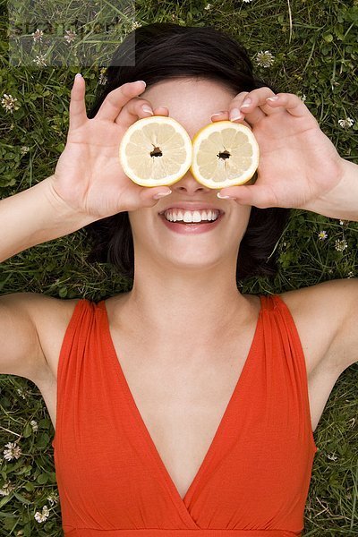 Junge Frau bedeckt ihre Augen mit Zitronenscheiben