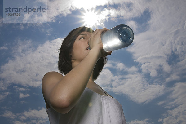 Junge Frau im Freien trinkt aus einer Wasserflasche