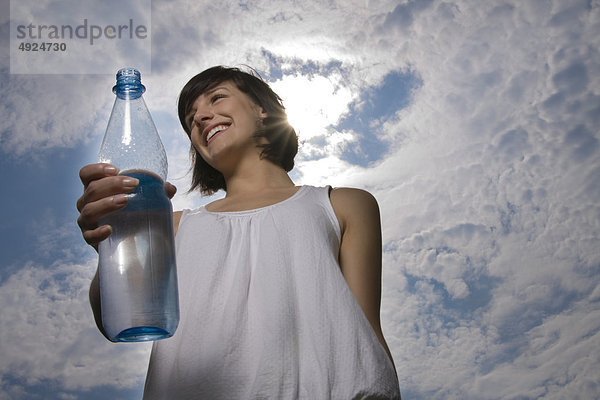 Junge Frau im Freien hält eine Wasserflasche
