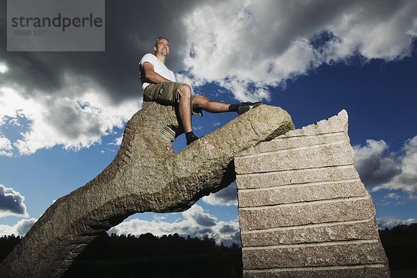 Man sitzt auf Denkmal unter Bedeckter Himmel