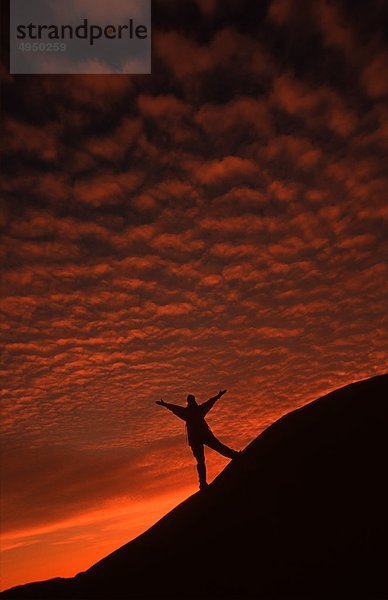 Eine Person stehen auf Hügel und Anhebung Hände  sunset