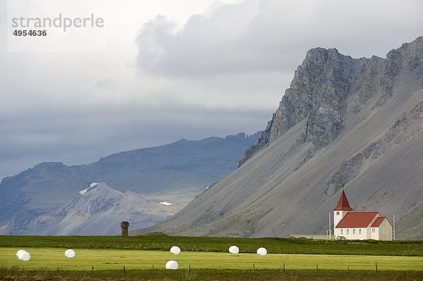 Ansicht der Kirche in Feld mit Bergen im Hintergrund