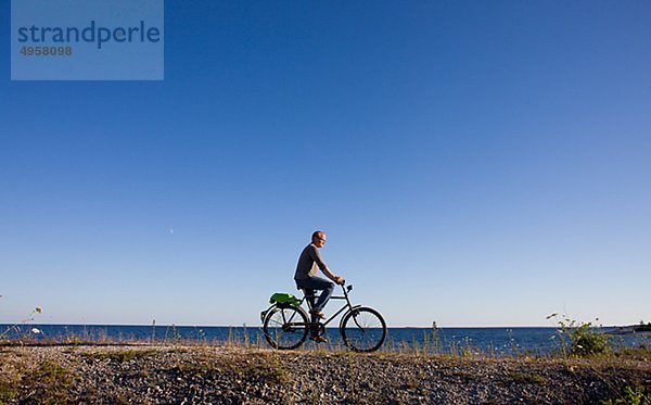 Man Fahrradfahren am Strand