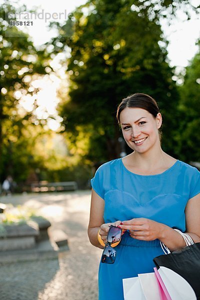 Lächelnde Frau stehend mit der hält Einkaufstaschen