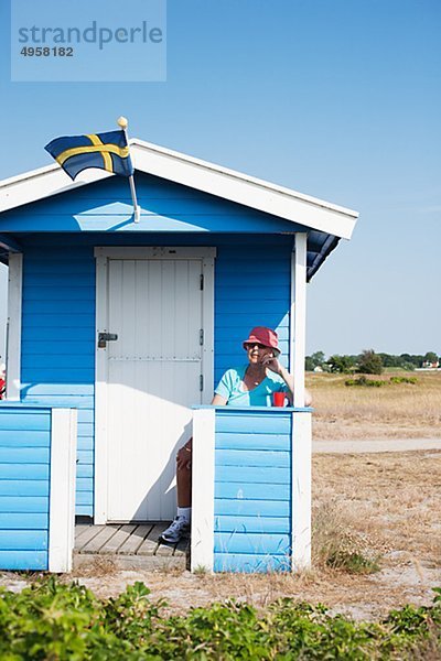 Frau sitzt vor Badhütte am Strand