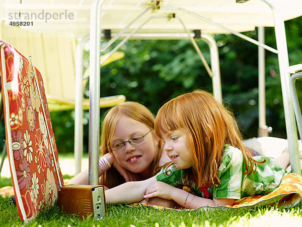 Zwei Mädchen unter outdoor Tisch liegend und Radio hören