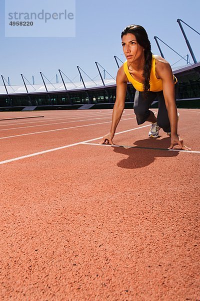 Weibliche Läufer auf Startblock im Stadion