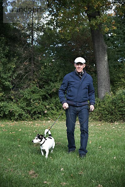 älterer Mann standing on Gras mit Hund