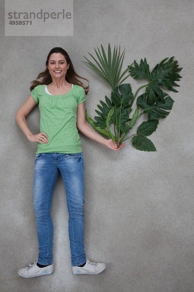 Mittlere erwachsene Frau hält Pflanze  Porträt  lächelnd