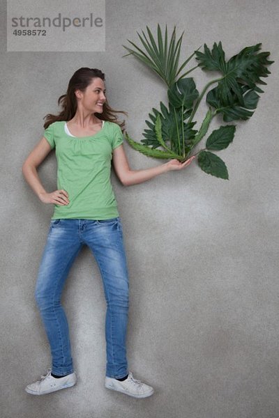 Mittlere erwachsene Frau hält Pflanze  lächelnd