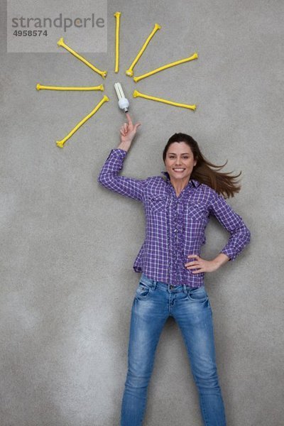 Mittlere erwachsene Frau zeigt auf Glühbirne  lächelnd  Portrait