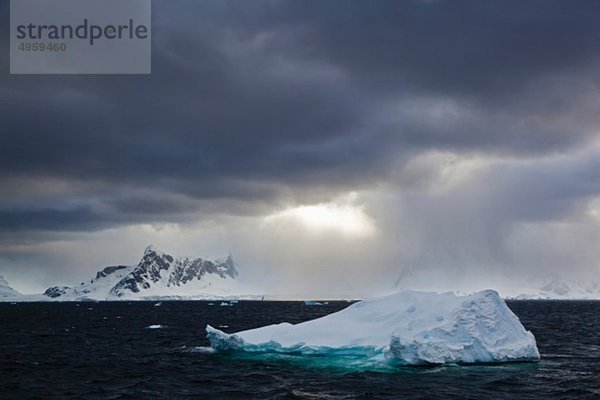 Südatlantik  Antarktis  Antarktische Halbinsel  Gerlache Straße  Eisberg mit schneebedeckter Bergkette bei Sonnenaufgang