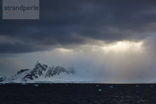 Südatlantik  Antarktis  Antarktische Halbinsel  Gerlache Straße  Eisberg mit schneebedeckter Bergkette bei Sonnenaufgang