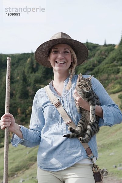 Österreich  Salzburger Land  Filzmoos  Junge Frau mit Katze  lächelnd  Portrait