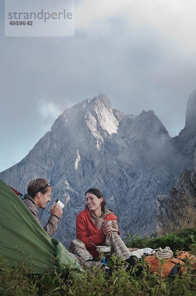 Österreich  Salzburg  Filzmoos  Paar sitzend neben Zelt am Berg