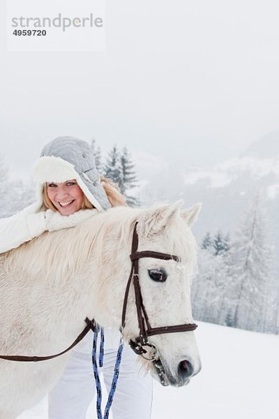 Österreich  Salzburg  Hüttau  Junge Frau mit weißem Pferd  lächelnd  Portrait