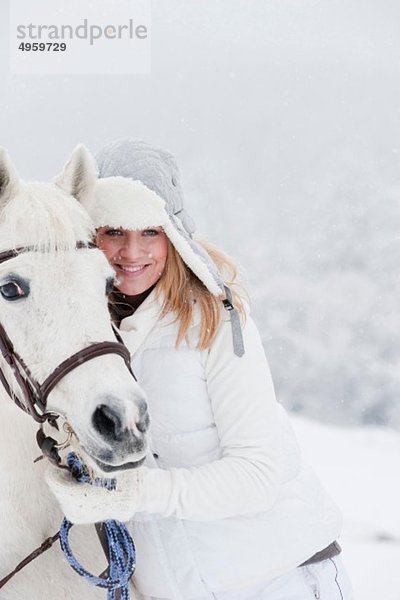 Österreich  Land Salzburg  Hüttau  Frau mit Pferd im Schnee stehend