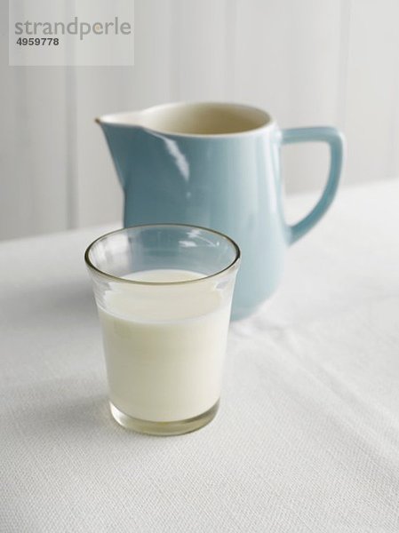 Glas Milch und Krug auf dem Tisch