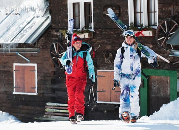 Österreich  Kleinwalsertal  Frauen mit Ski auf den Schultern bei der Berghütte