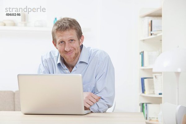 Mann mit Laptop zu Hause  lächelnd  Portrait