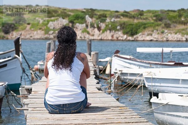 Spanien  Balearen  Menorca  Mittlere erwachsene Frau entspannt am Steg