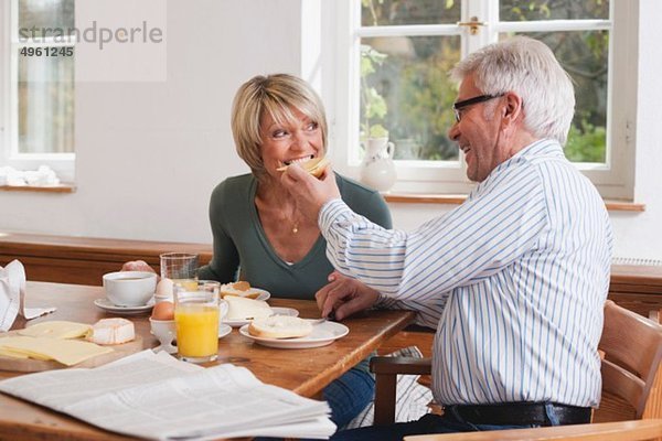 Älterer Mann füttert Frühstück an ältere Frau