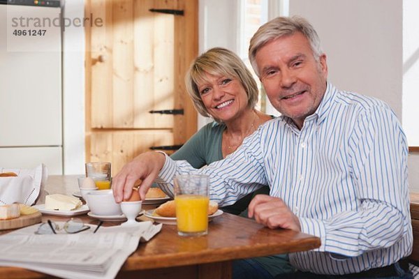 Deutschland  Kratzeburg  Seniorenpaar beim Frühstück  lächelnd  Portrait