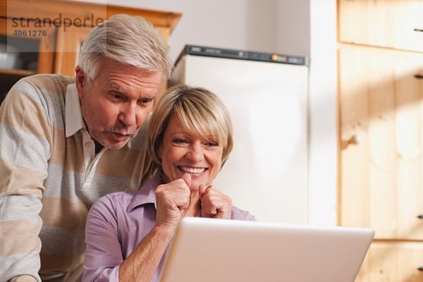 Deutschland  Kratzeburg  Senior Paar mit Laptop  lächelnd
