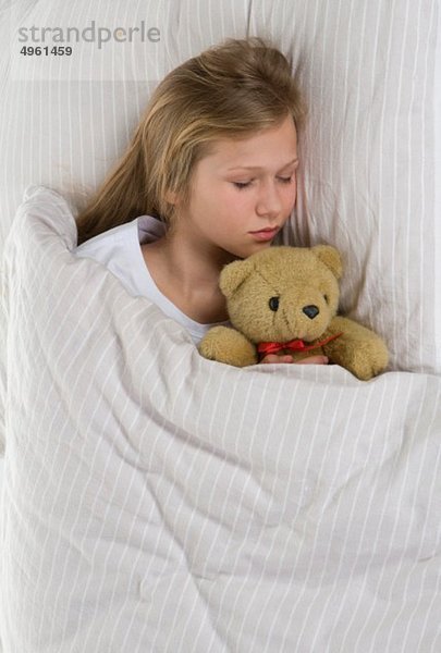 Mädchen schläft auf Bett mit Teddybär
