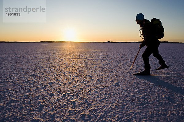 Mann Eislaufen auf Schnee bedeckt Landschaft in der Dämmerung