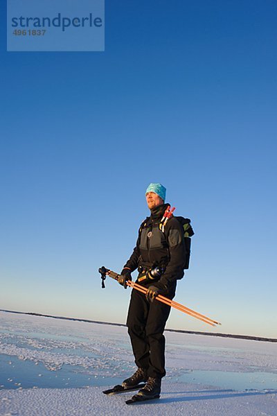 Man standing on verschneite Landschaft hält Skistock
