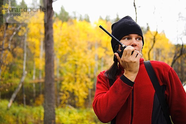 Frau mit Funksprechgerät im Wald