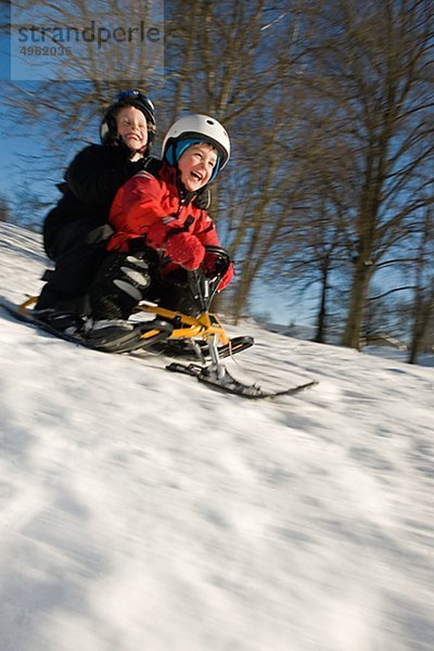Jungen und Mädchen Rodeln auf Schnee