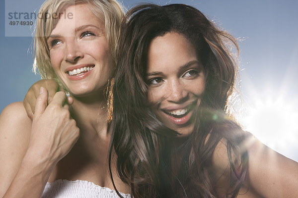 Zwei fröhliche junge Frauen unter blauem Himmel