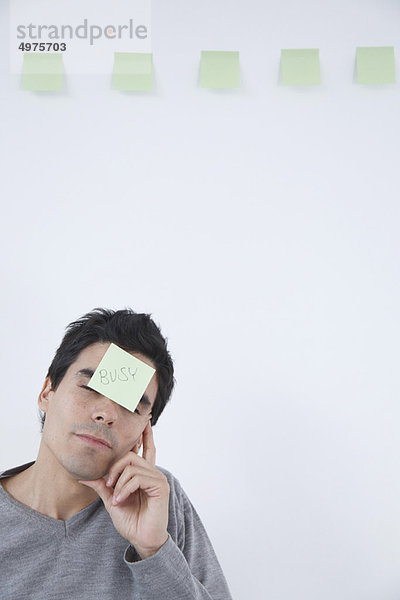 Mann mit'beschäftigter' Post-It Notiz auf dem Kopf