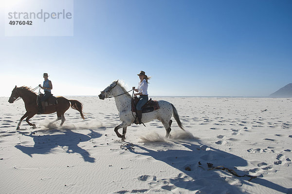 2 Personen auf Pferden im Sand
