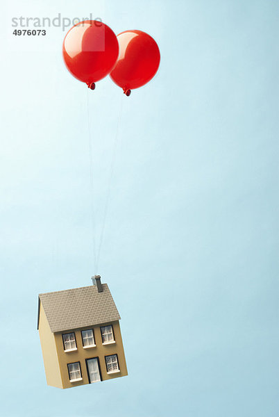 Haus schwebt mit zwei Luftballons davon