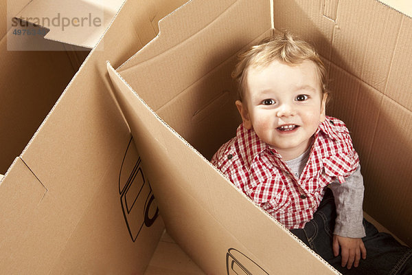 Kleiner Junge sitzend in der Packkiste